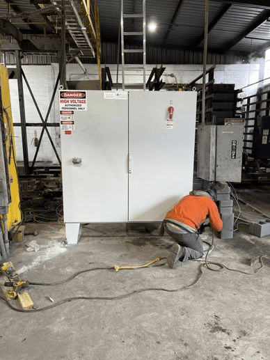 A man in an orange shirt is working on a cabinet.