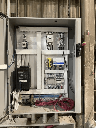 A view of an electrical panel with wires and boxes.